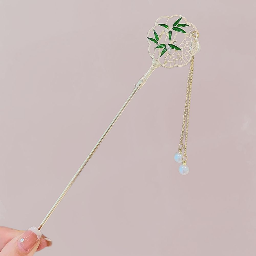 Bâtonnet en métal doré avec motif floral vert et perles nacrées, sur fond rose