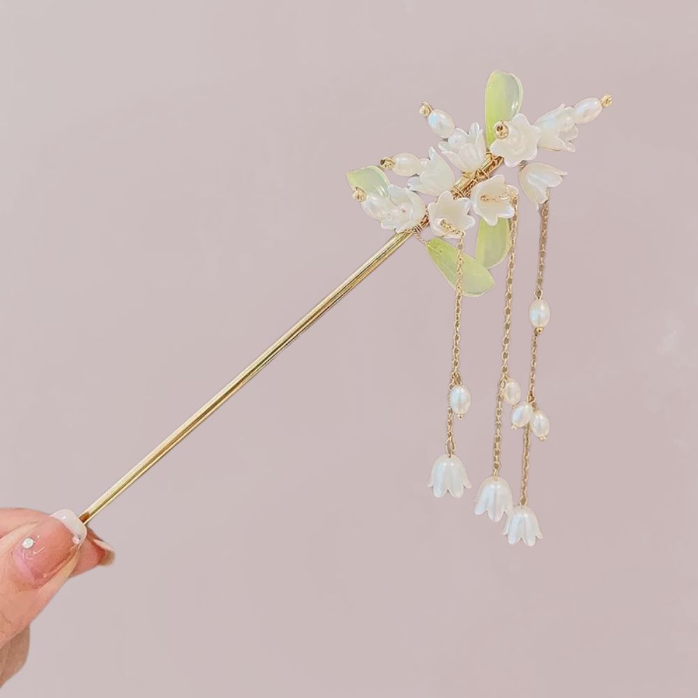 Bijou de cheveux doré avec fleurs blanches et perles en cascade, sur fond rose doux
