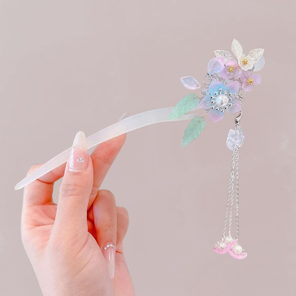 Peigne en résine translucide avec fleurs pastel et gouttes de cristal rose, tenu délicatement par une main