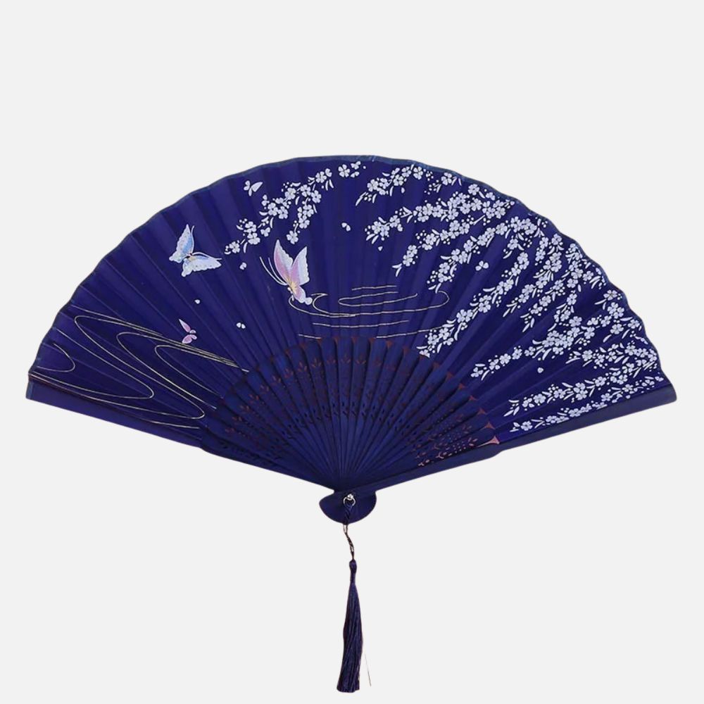 Éventail en soie bleu foncé décoré de fleurs blanches et de papillons colorés, avec un pompon en bas