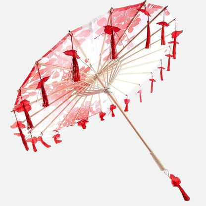 Ombrelle rouge ornée de motifs floraux et de pompons, avec une structure en bois délicate et raffinée