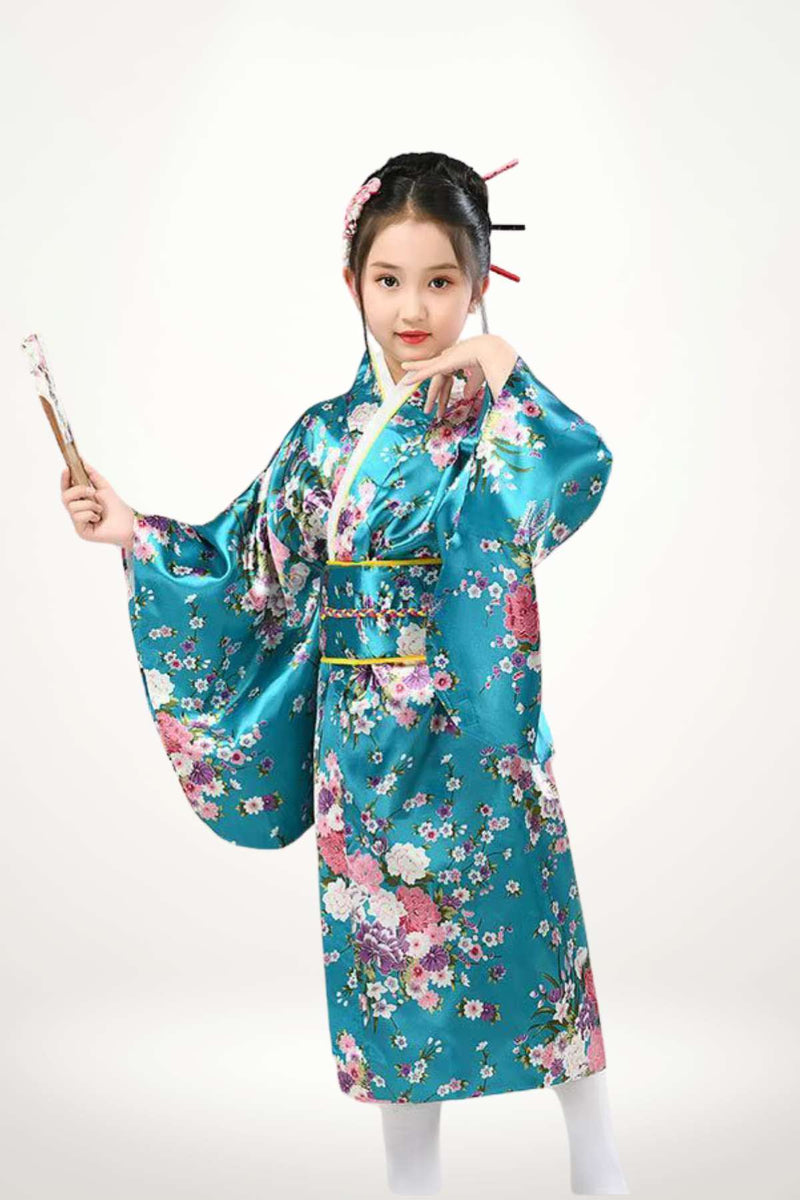 Fillette portant un kimono bleu pétrolé orné de fleurs colorées, posant avec élégance et un éventail en bois