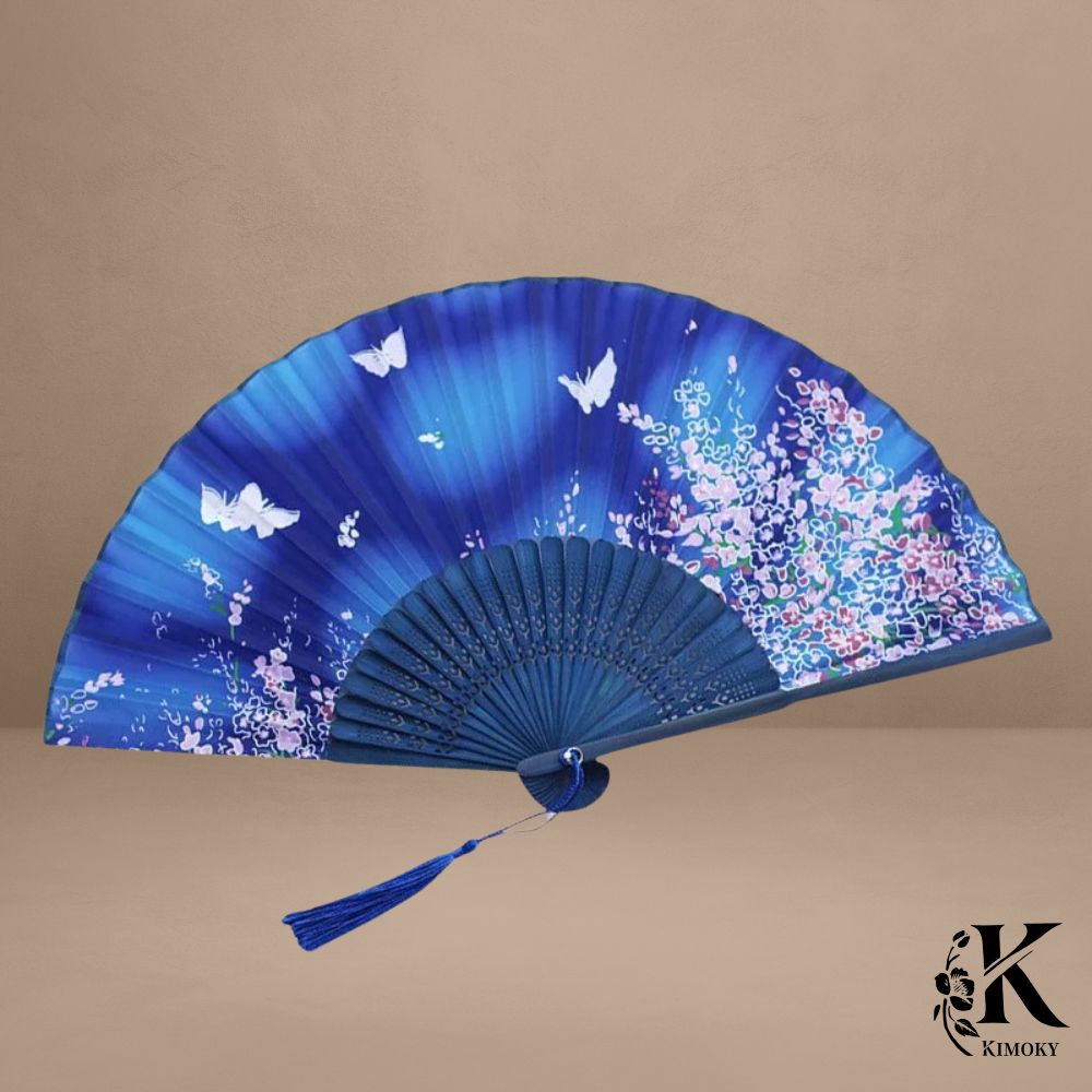 Éventail japonais bleu nuit avec papillons blancs et fleurs roses, accessoire raffiné pour kimono femme ou tenue estivale chic