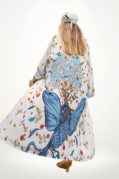 Femme portant un kimono long aux motifs colorés de fleurs et d'oiseaux, sur fond clair, avec des sandales marron