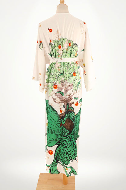Kimono en satin blanc avec motifs verts de paon et fruits, dans un décor épuré et lumineux