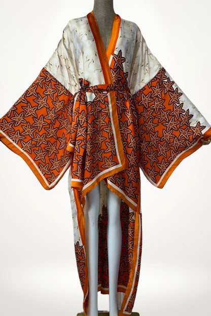 Kimono satin femme orange crème à imprimé feuilles, manches amples et ceinture fluide, coupe asymétrique élégante.