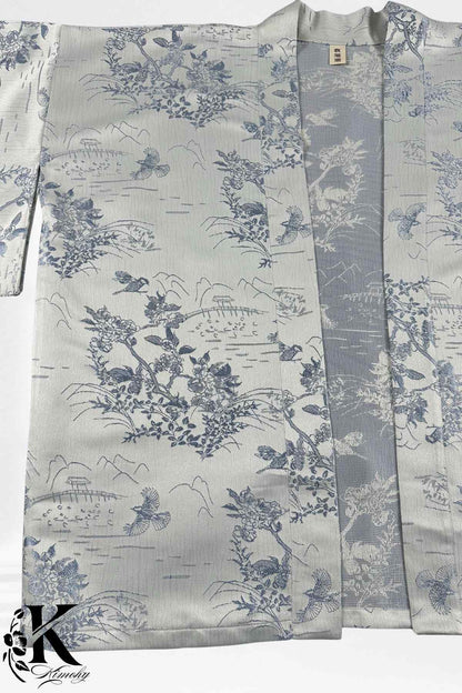 Kimono élégant en satin argenté avec motifs floraux bleus et oiseaux, ouvert au centre sur fond clair