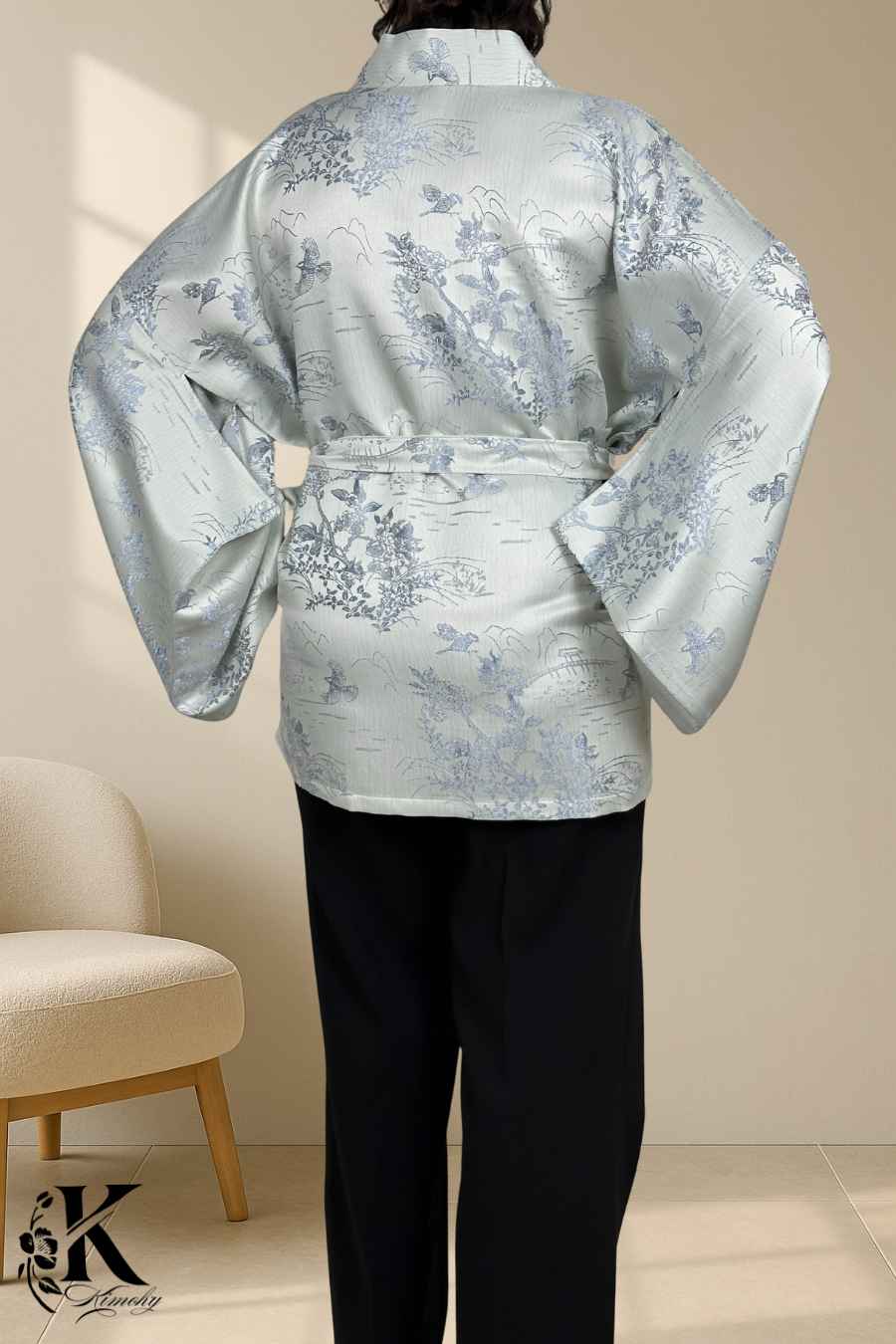 Kimono en satin argenté avec motifs floraux bleus, porté avec un pantalon noir dans un décor sobre