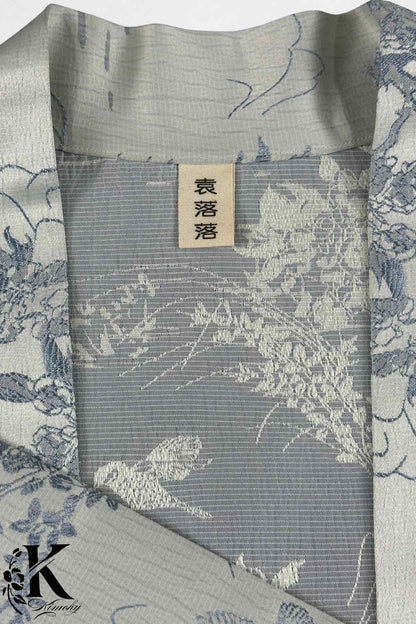 Détail d'un kimono en tissu gris clair avec motifs floraux bleu et blanc, élégant et raffiné