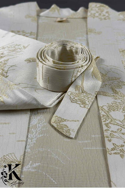 Un kimono élégant en tissu beige clair avec des motifs dorés et un obi enroulé à côté