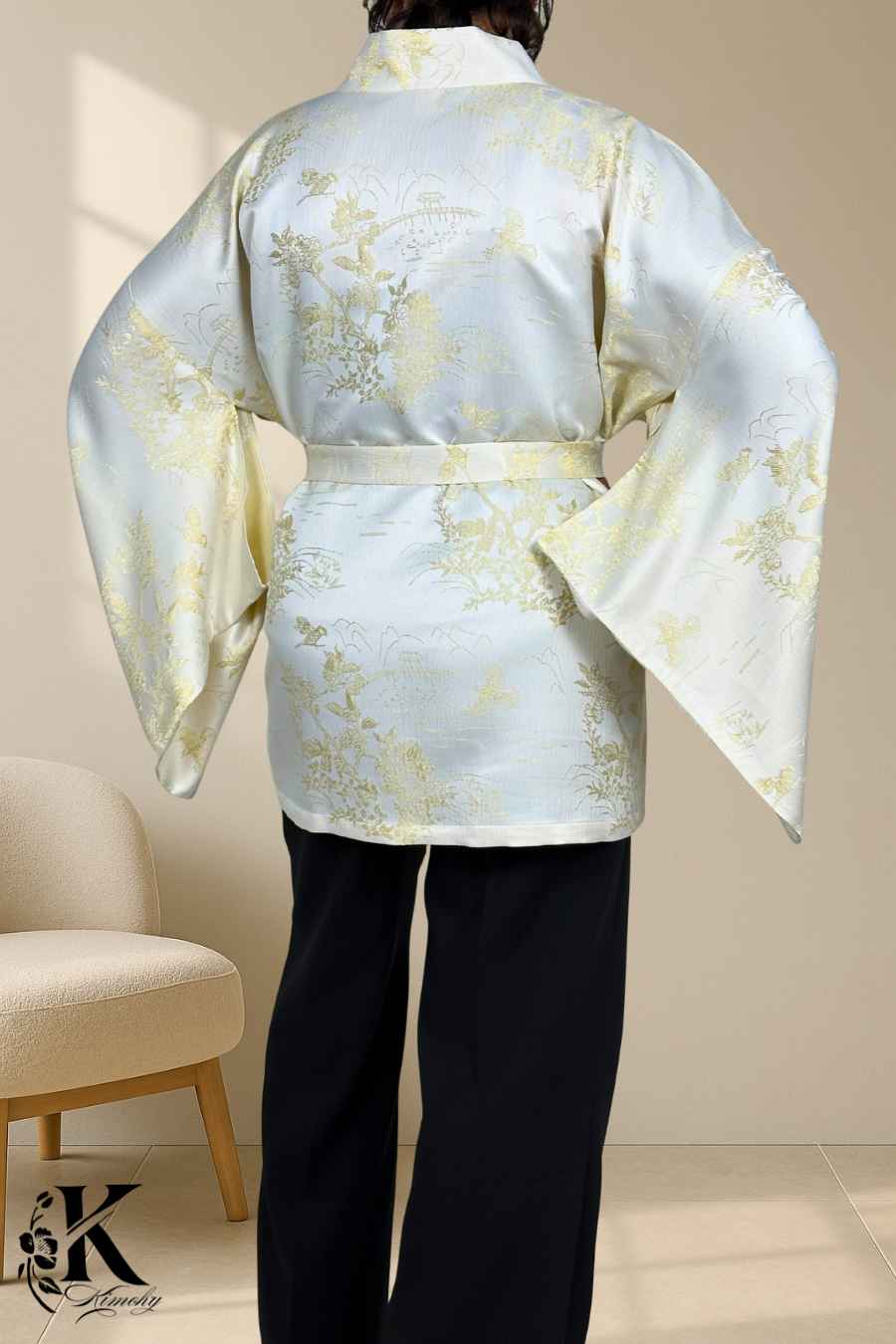Kimono chic en satin blanc avec motifs dorés, porté avec un pantalon noir, dans un décor sobre et élégant