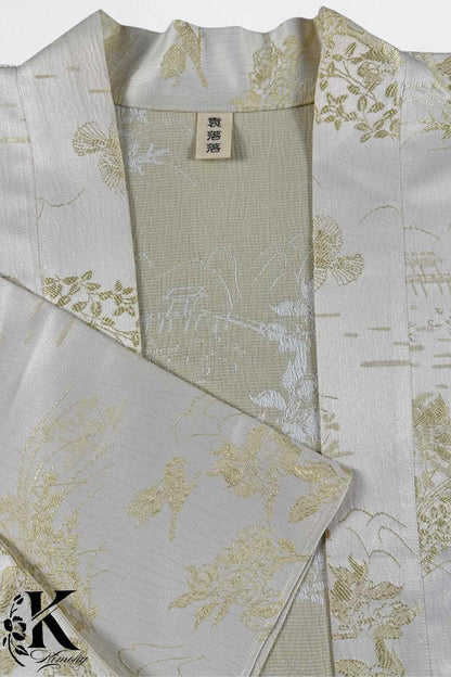 Kimono en soie blanche avec motifs floraux dorés sur fond beige, élégant et raffiné, évoquant le style japonais