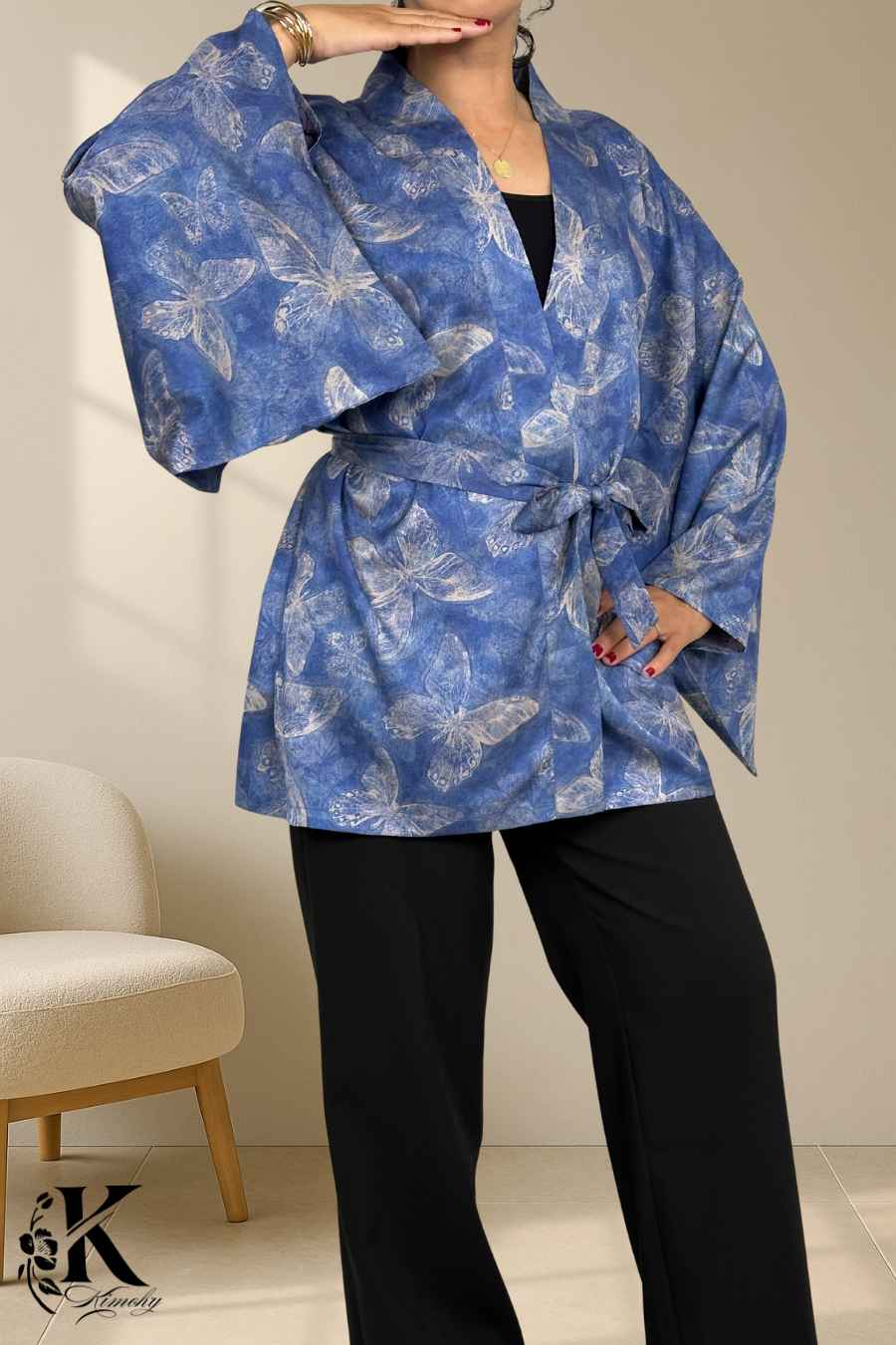 Kimono bleu avec motifs de papillons, manches larges, porté avec un pantalon noir sur fond clair