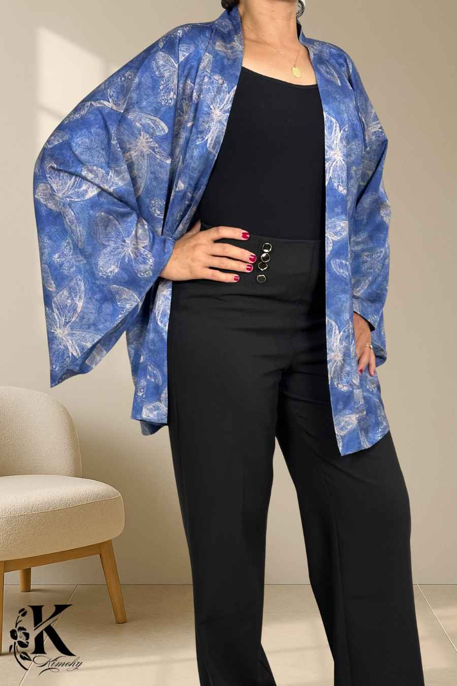 Femme portant un kimono bleu floral avec des motifs de papillons, associé à un pantalon noir élégant