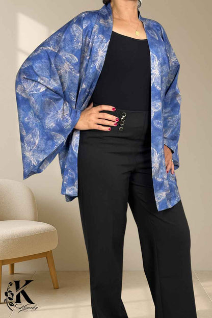 Femme portant un kimono bleu floral avec des motifs de papillons, associé à un pantalon noir élégant