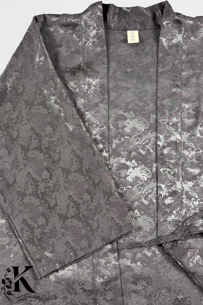Kimono en satin gris avec motifs floraux délicats et reflets argentés, drapé élégamment sur un fond neutre