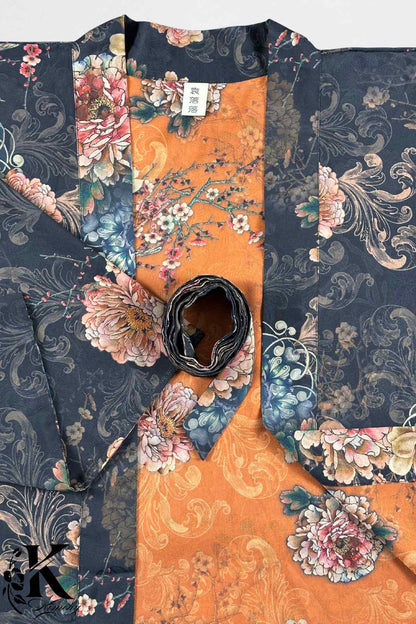 Kimono élégant avec motifs floraux colorés sur fond noir et orange, posé sur une surface claire