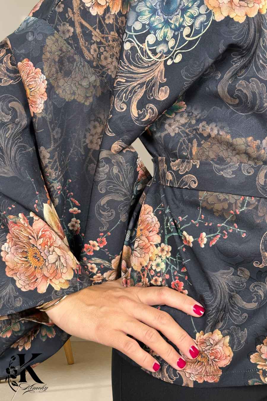 Kimono élégant à motifs floraux colorés sur fond noir, porté avec une main posée sur la taille