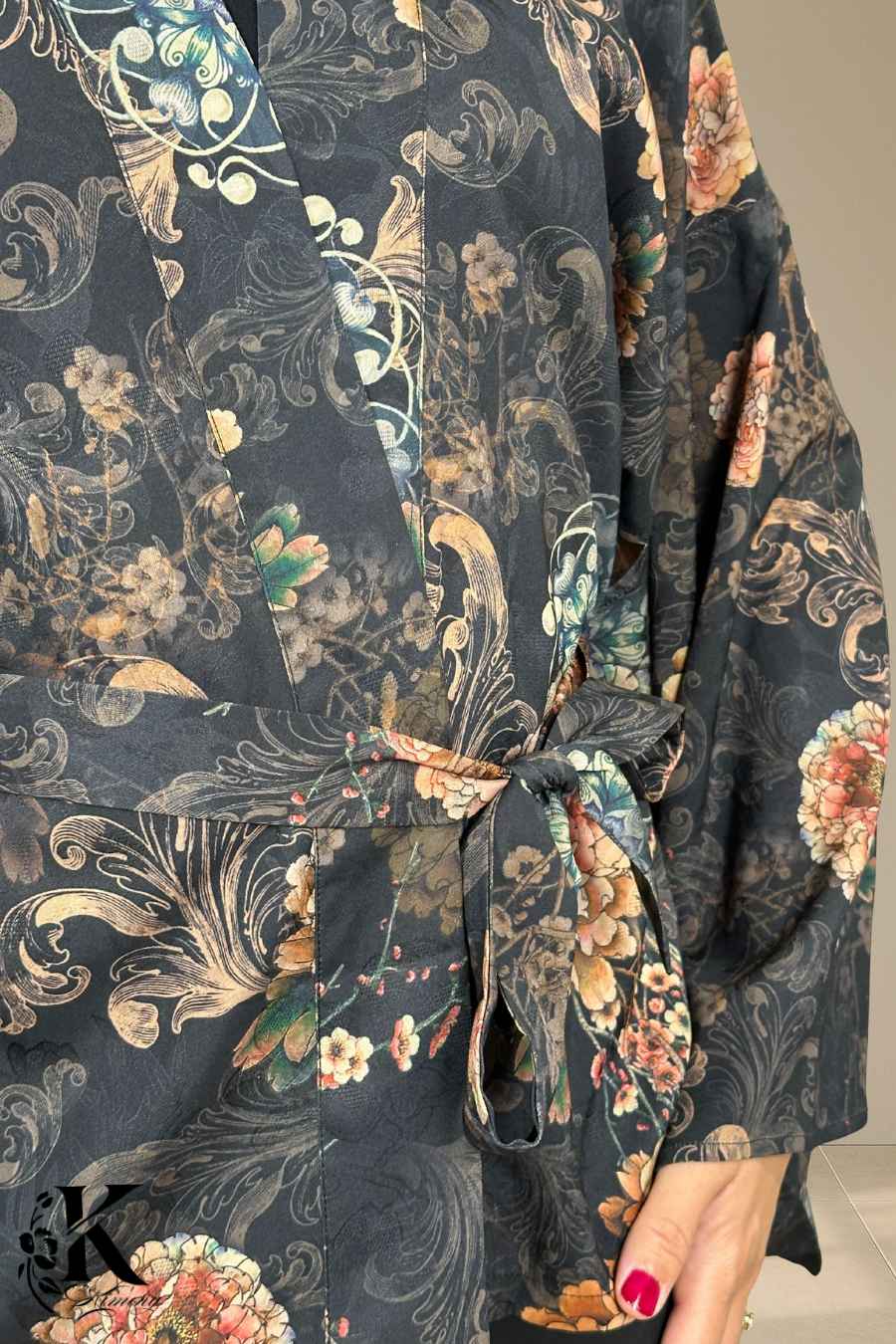 Kimono noir à motifs floraux colorés, ceinturé à la taille, porté dans un jardin obscur