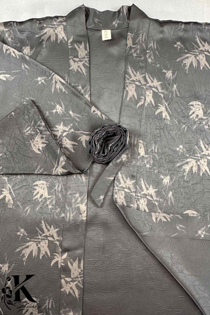Kimono en satin gris avec motifs de feuilles, tissu léger et texturé, drapé élégant sur fond neutre