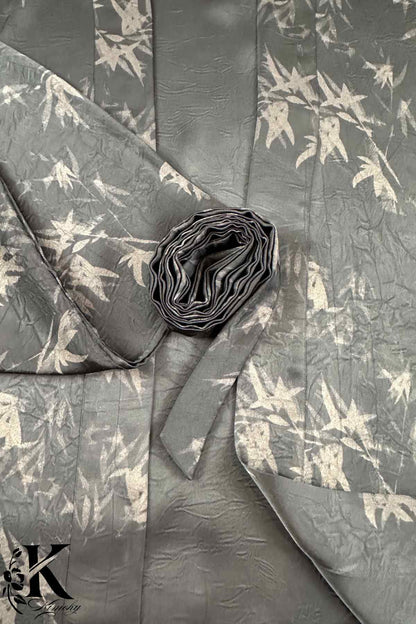 Un kimono chic en tissu gris avec motifs de feuilles claires, drapé élégamment et roulé sur le côté