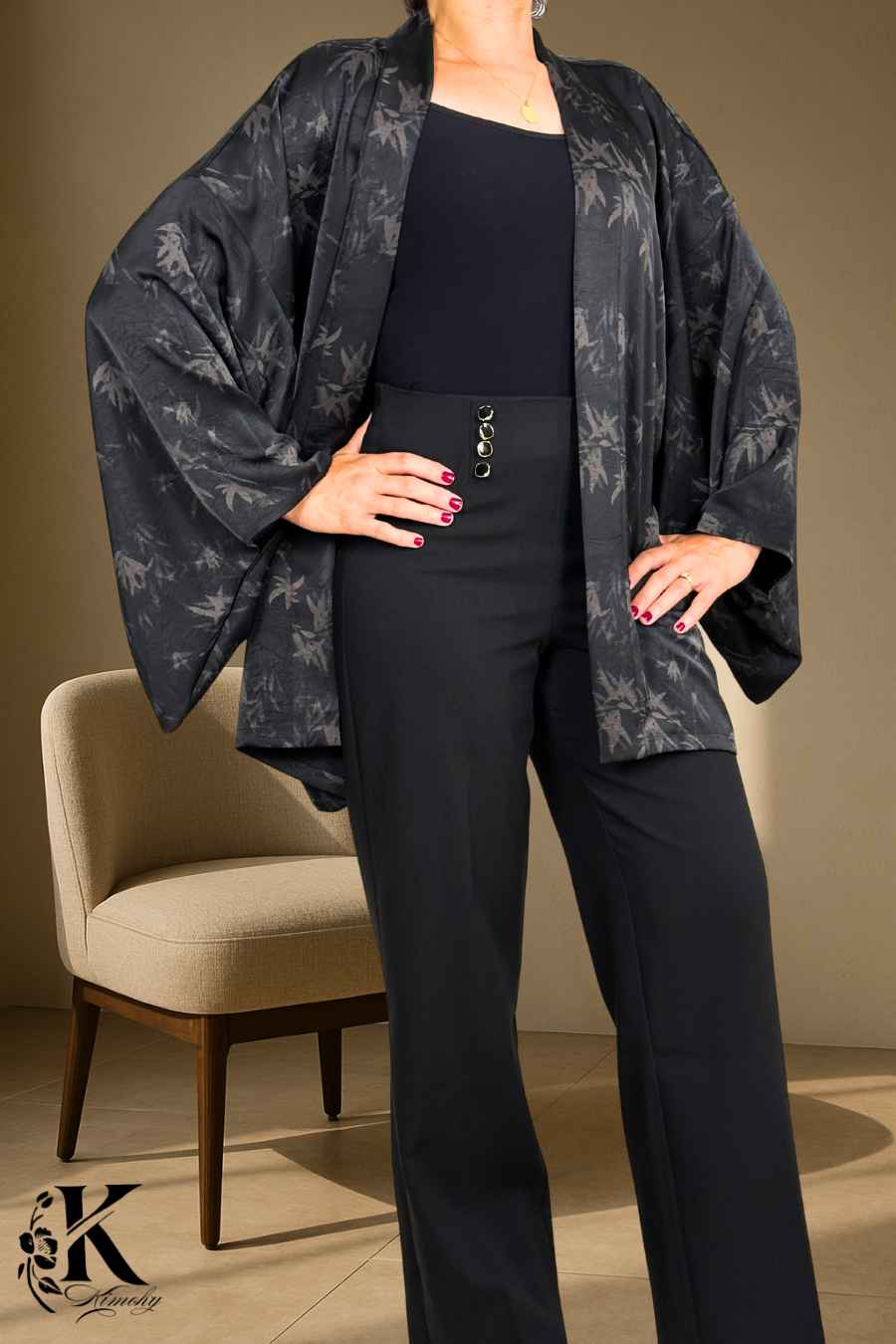 Femme portant un kimono noir à motifs, avec un pantalon noir, dans un décor sobre et élégant