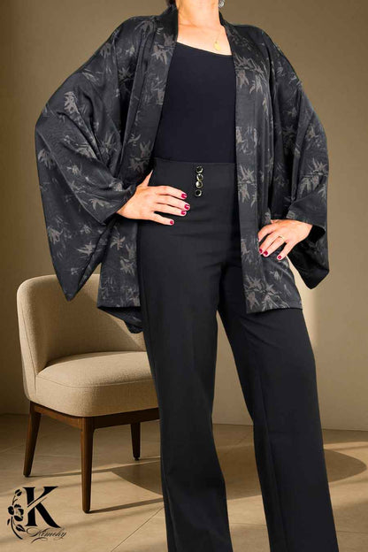 Femme portant un kimono noir à motifs, avec un pantalon noir, dans un décor sobre et élégant
