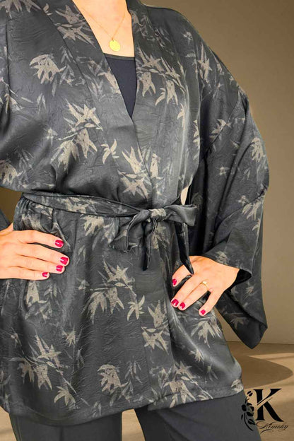 Kimono noir avec motifs de feuilles grises, ceinturé, porté par une femme dans un décor sobre