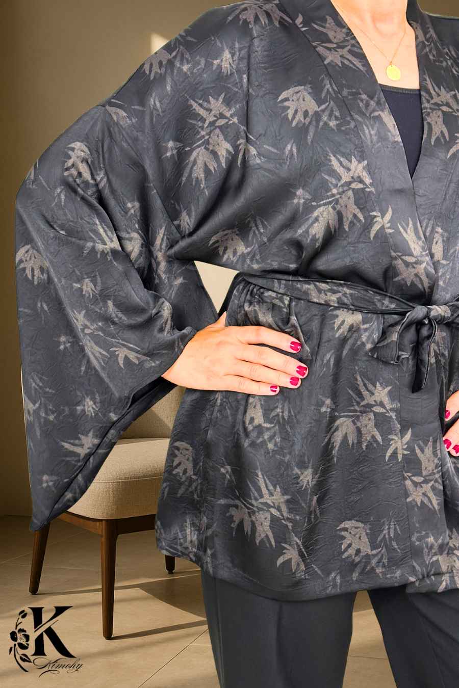 Kimono noir à motifs de feuilles, ceinturé à la taille, porté avec un fond clair et décor élégant