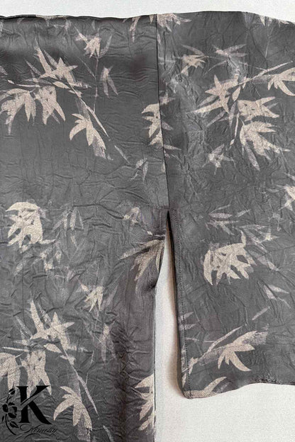 Kimono en tissu noir avec motifs de feuilles claires, présentant une texture légèrement froissée et une coupe élégante
