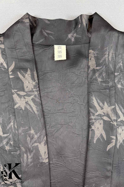 Kimono en tissu noir avec motifs floraux gris, présentant une texture douce et légèrement froissée