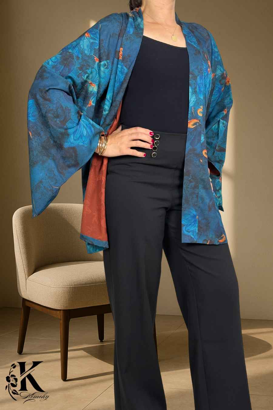 Femme portant un kimono bleu et orange avec motifs floraux, dans un décor sobre et élégant
