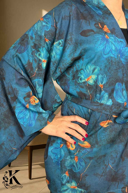 Kimono en tissu bleu avec motifs floraux, manches larges, porté avec une ceinture, dans un décor sobre