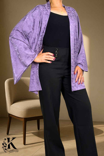 Veste kimono femme en satin violet, manches larges, portée avec un pantalon noir, fond décoratif clair