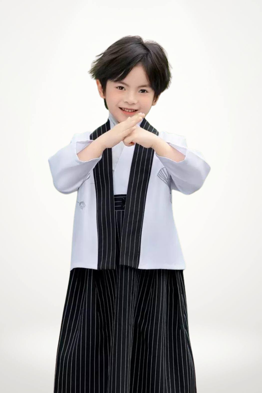 Un enfant porte un kimono blanc avec un pantalon noir à rayures, affichant une posture confiante et élégante