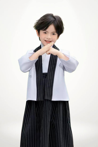 Un enfant porte un kimono blanc avec un pantalon noir à rayures, affichant une posture confiante et élégante