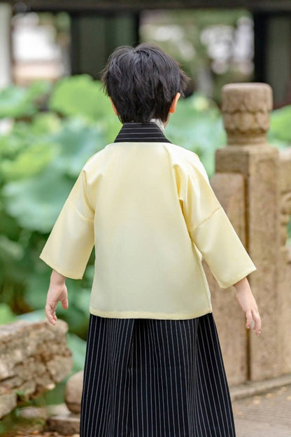 Un enfant de dos porte un kimono traditionnel japonais blanc et noir dans un jardin