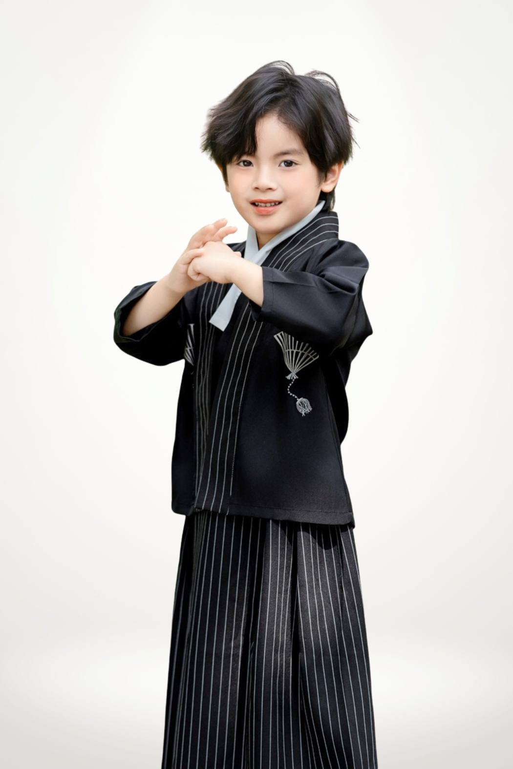 Un enfant porte un kimono noir à rayures avec un col blanc et des chaussons noirs, se tenant droit