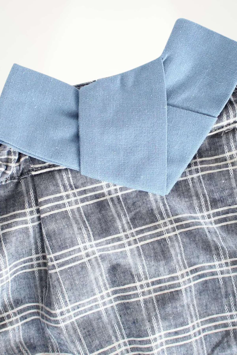 Détail d'un kimono bébé avec un col bleu et un motif à carreaux gris et blanc