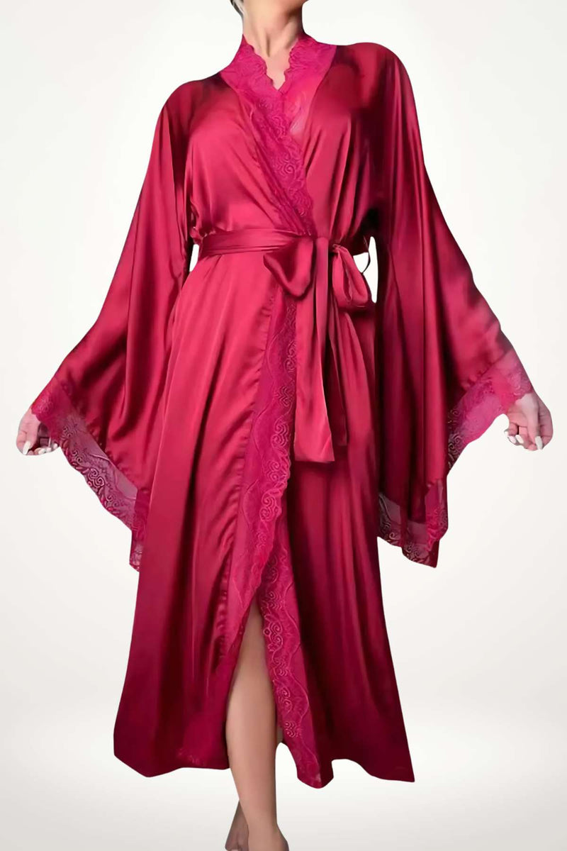 Femme en kimono rouge satiné avec des manches larges, dentelle rose, posée sur un fond clair