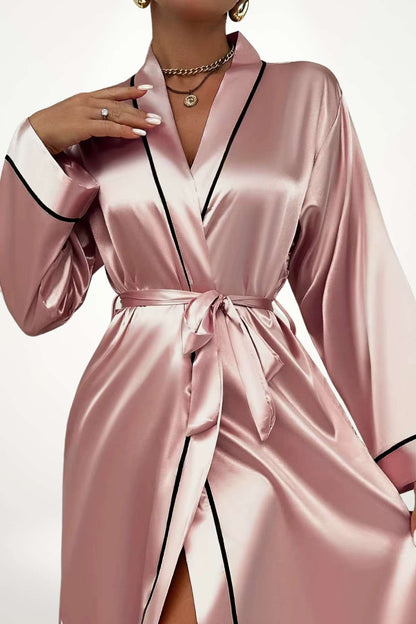 Kimono en satin rose avec des détails noirs, drapé élégant et ceinture nouée, posé sur un fond blanc