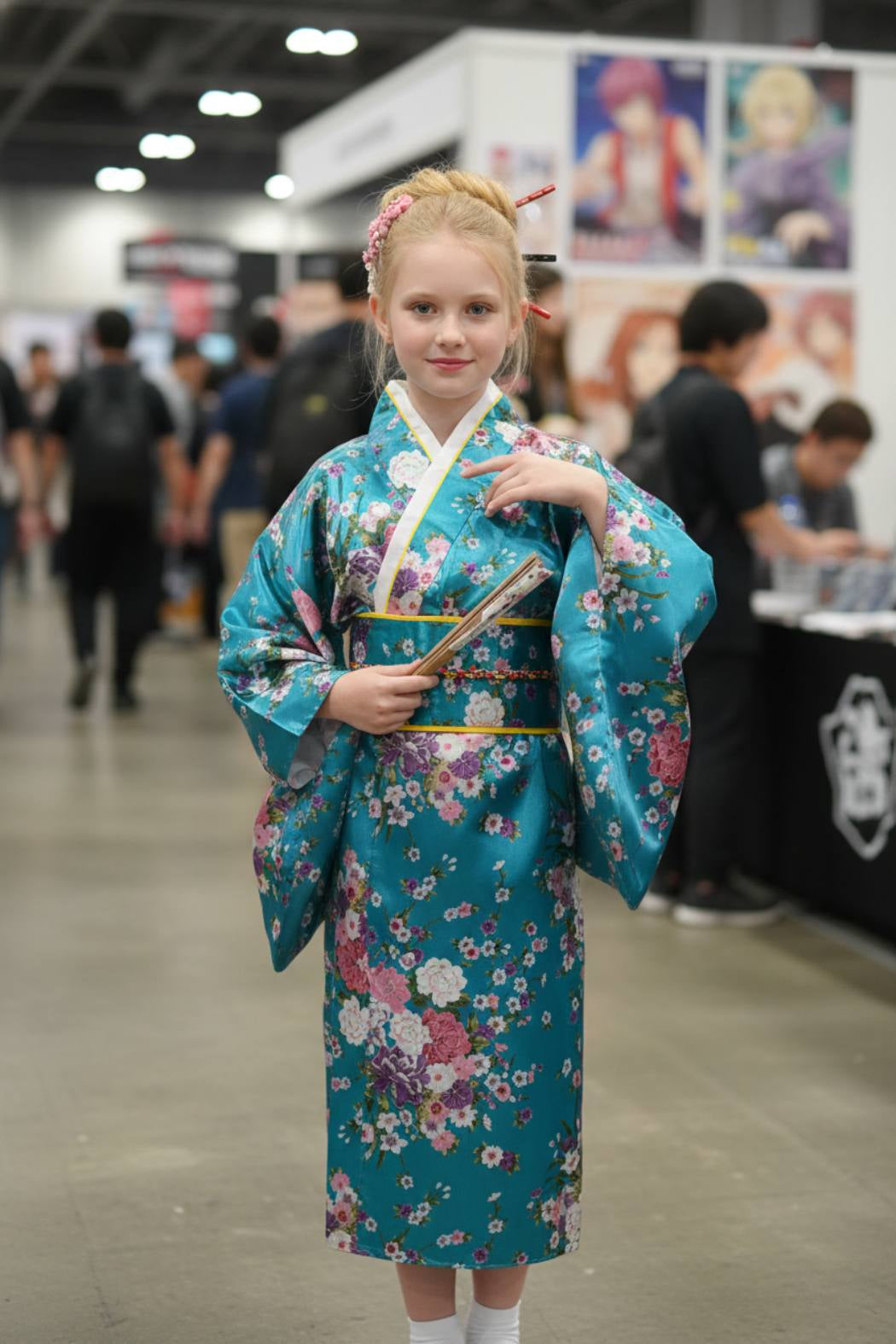 Fillette en kimono bleu turquoise orné de fleurs, tenant un éventail, à une japan expo