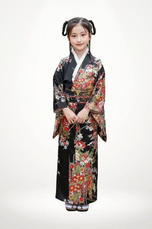 Fillette souriante en kimono noir orné de fleurs rouges et blanches, posant avec les mains jointes