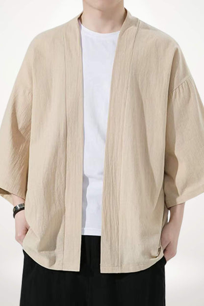 Homme portant un kimono beige léger avec un t-shirt blanc, dans un décor minimaliste et apaisant