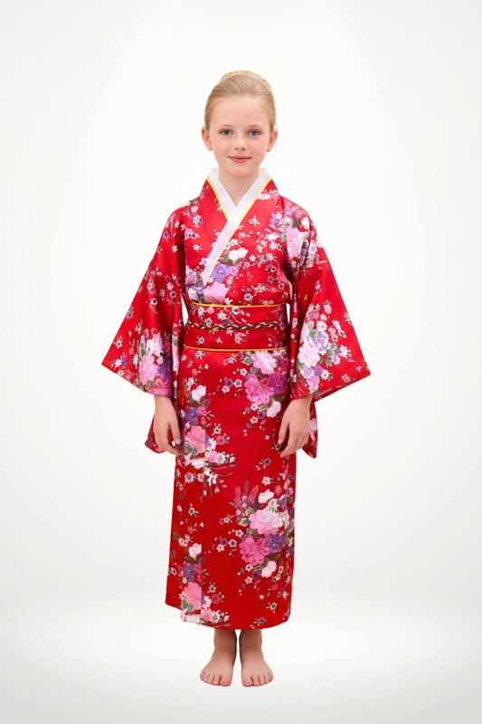 Fillette en kimono rouge à motifs floraux, posant avec une main délicate sur un fond neutre