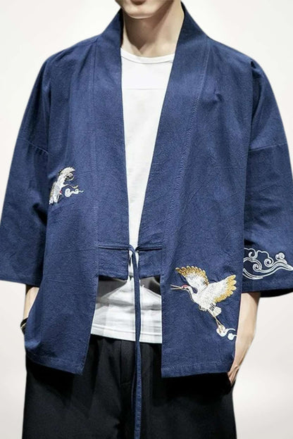 Un homme porte un kimono japonais bleu avec des motifs brodés de nuages et d'oiseaux