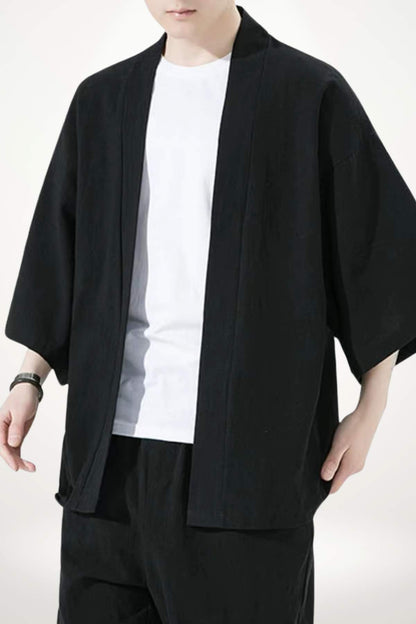 Homme portant un kimono noir élégant, avec un t-shirt blanc, dans un décor minimaliste et lumineux