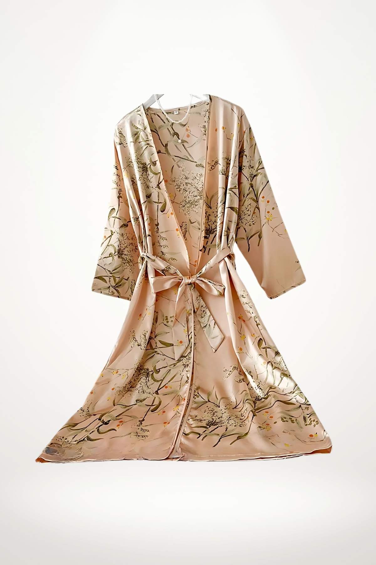 Peignoir kimono en satin rose avec motifs floraux verts et jaunes, noué à la taille, suspendu sur fond blanc