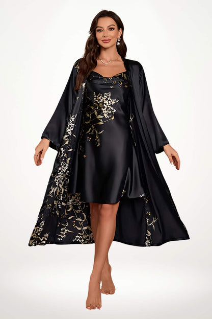 Femme en peignoir noir satiné avec motifs floraux dorés, posant élégamment sur un fond clair