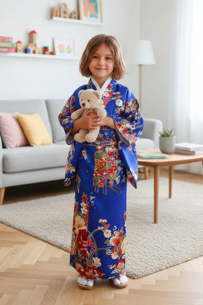 Fillette souriante en kimono bleu orné de fleurs colorées, posant avec sa peluche